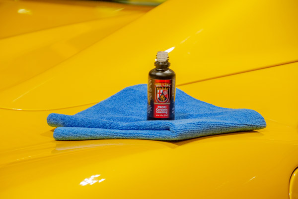 This image shows the after effects of the Wolfgang PROFI Ceramic Coating. The paint is glossy and the bottle of ceramic coating is sitting on top of a microfiber towel on the car's hood.